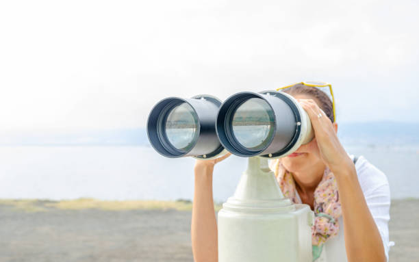 Woman tourist looks through a spyglass in the open. Woman tourist looks through a stationary spyglass in the open. hiding place stock pictures, royalty-free photos & images