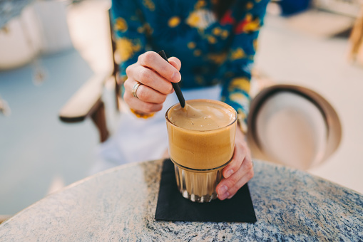 Woman at beach cafe is mixing frappe with drinking straw