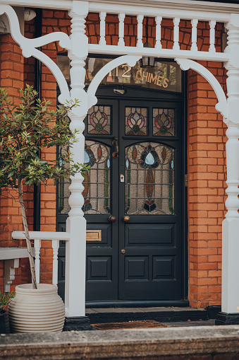 London, UK - May 26, 2020: Black stained glass front door of a traditional Edwardian house in London, selective focus. Edwardian houses promote simple design and an appreciation for the handmade.
