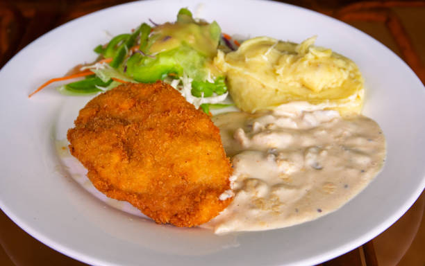 istock Schnitzel with mashed potato on white plate. Fried chicken cutlet top view photo on wooden table. Tasty lunch served 1248243224