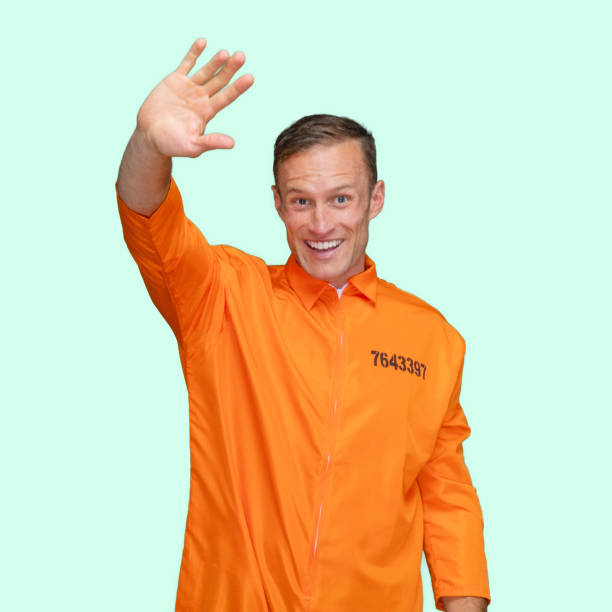 Criminal standing in front of colored background wearing jumpsuit