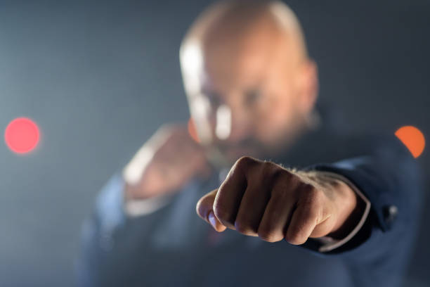 Front view of aged 40-44 years old with brown hair caucasian male standing in front of white background wearing glove and boxing who is punching