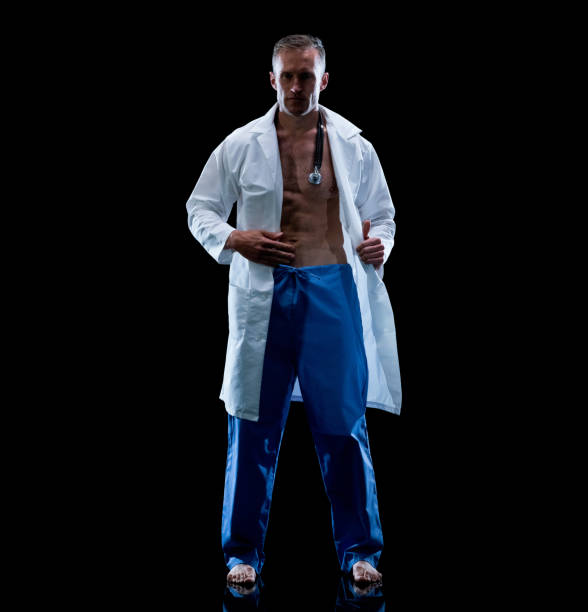 caucasian male doctor standing in front of black background wearing lab coat - sensuality men shirtless studio shot imagens e fotografias de stock