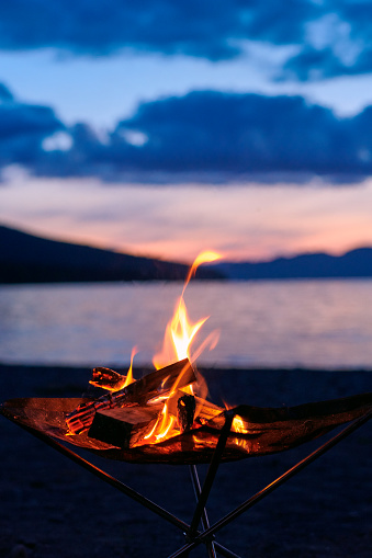 Vertical photo of bonfire time starting at dusk at lakeside camp