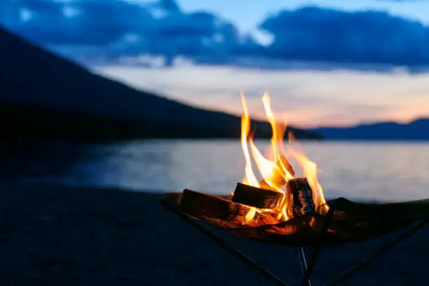 Bonfire time beginning at dusk at lakeside camp