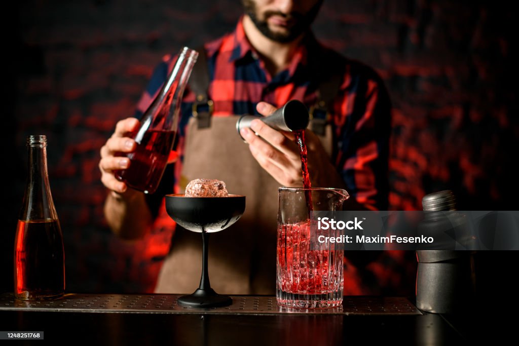 Bartender Pours Red Liquid From Jigger Into Mixing Cup Stock Photo