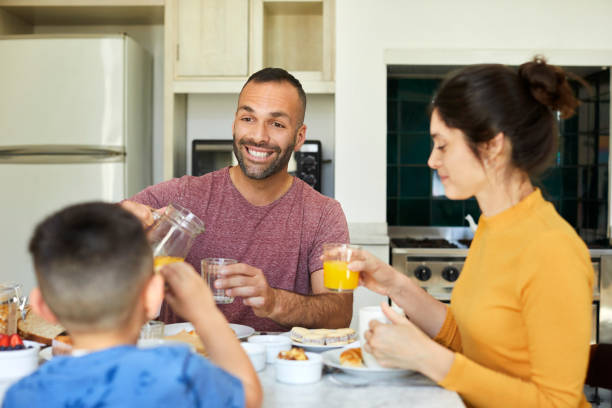 istock Smiling man looking at son while pouring juice 1248253781