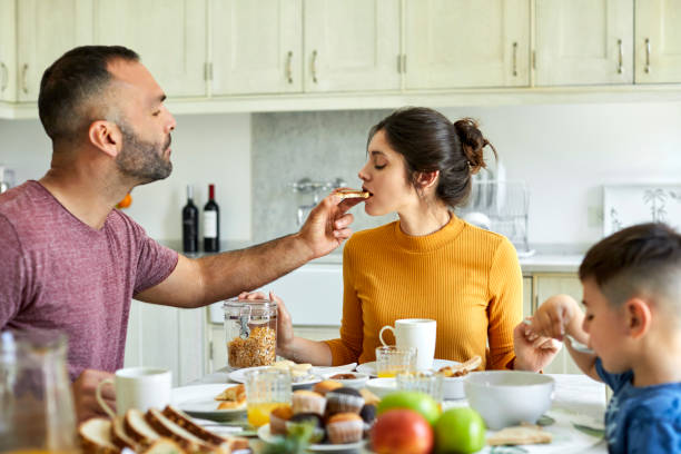 istock Man feeding bread toast to woman in kitchen 1248254327