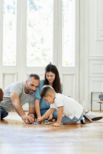 famiglia che gioca con le auto giocattolo in soggiorno - floor two parent family couple home interior foto e immagini stock