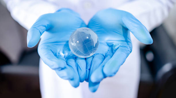Doctor hand holding world crystal ball Global health and medicine. Heal the world concept. Doctor, nurse or medical worker in white protective suit with blue sterile rubber gloves holding world globe crystal glass ball in hand. hand-hygiene-day stock pictures, royalty-free photos & images