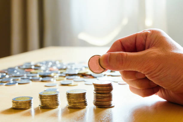 istock Selective focus Asian men hand put coin into stack with piggy bank on background. Saving plan for retirement planning, pension, tax reduction. Wealth and good financial or money investment concept. 1248255246