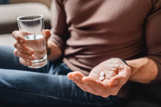 nahaufnahme des seniors, der medikamente mit wasser nimmt - prozac stock-fotos und bilder