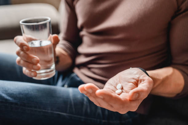 水で薬を飲む先輩男性のクローズアップ - prozac ストックフォトと画像
