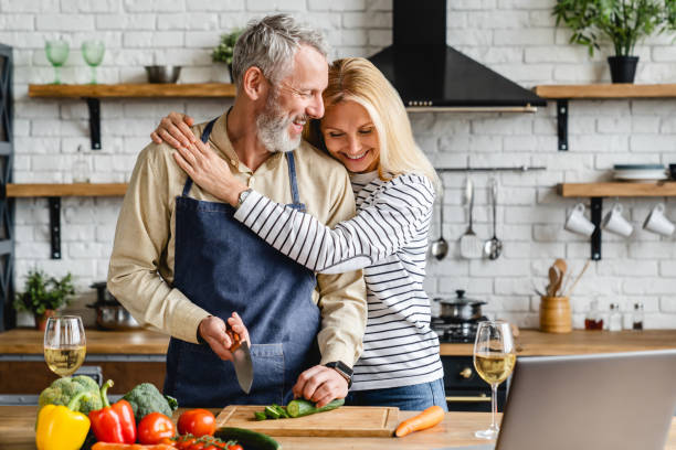 istock Beautiful mature couple hugging while cooking vegetable salad at kitchen table 1248256211