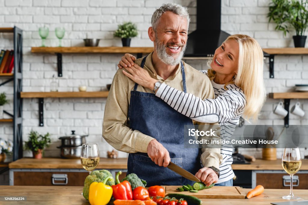 Senior couple spending time together while cutting vegetables at kitchen People, Senior Couple, Indoors, Family, Love-Emotion Cooking Stock Photo