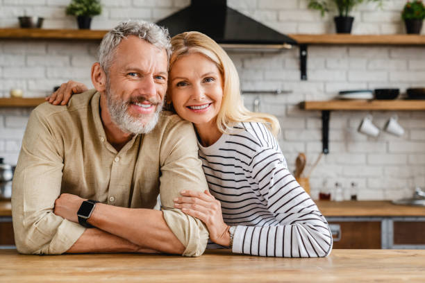Portrait of middle aged couple hugging while standing together in kitchen at home People, Senior Couple, Indoors, Family, Love-Emotion mature couple photos stock pictures, royalty-free photos & images
