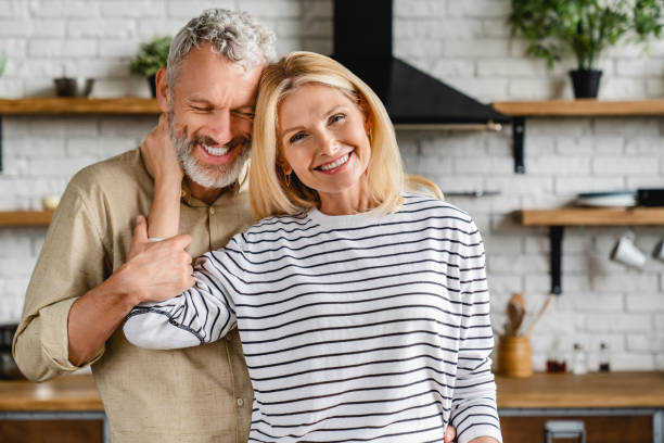 自宅のキッチンで抱き合う幸せな中年カップル - 40s mature couple couple smiling ストックフォトと画像