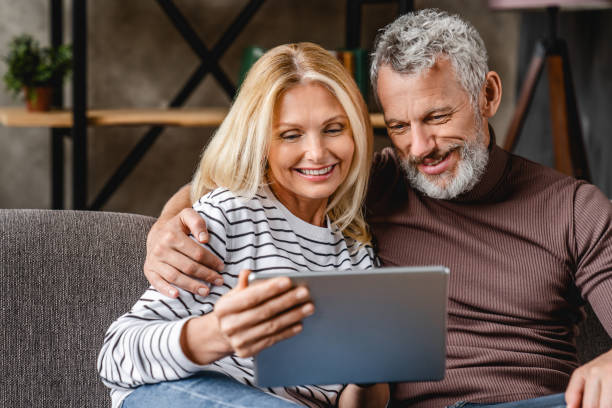 istock Smiling middle aged couple using digital tablet on sofa at home 1248256682