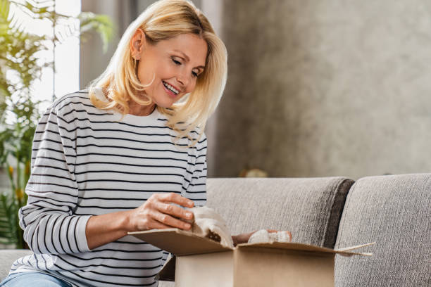 istock Happy middle aged woman customer taking out from box her shipment parcel at home 1248256892