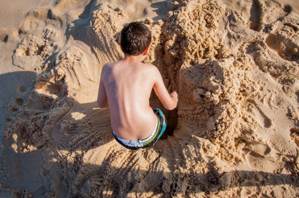 Boy burying himself on the beach sand