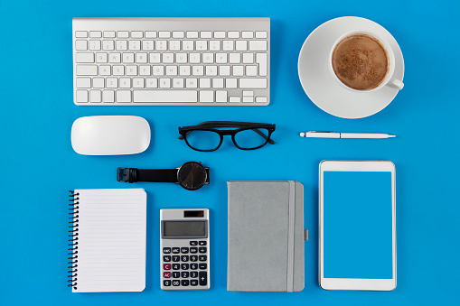 Directly above view of office equipments  and digital tablet with copy space on blue background