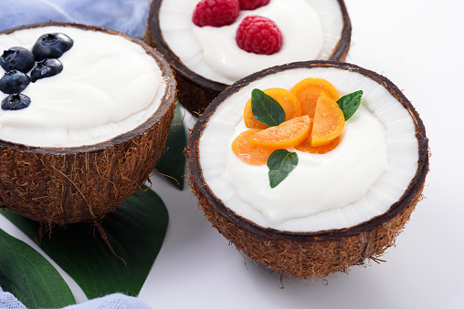 ice cream with berries in coconut bowls, milkshake on white background, trendy exotic dessert