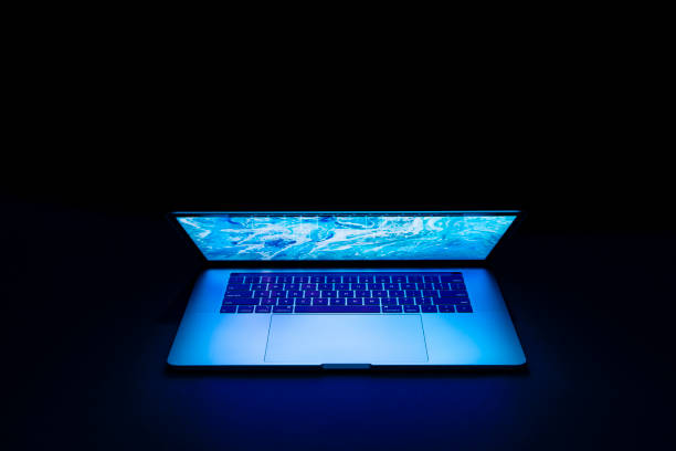 istock Isolated high tech open laptop with abstract vibrant blue color screen on a dark background. 1248264026