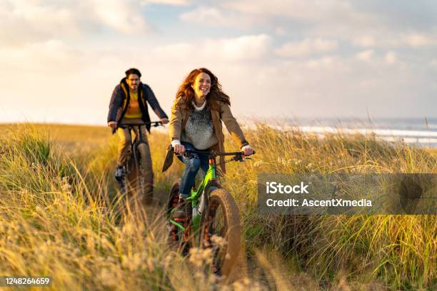Young Couple Ride Fat Bikes On Coastal Trail Stock Photo - Download Image Now - Cycling, Couple - Relationship, People