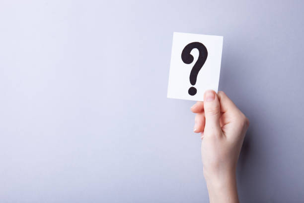 istock Woman holding card with question mark on color background. Paper note with question mark or sign against grey background, space for text. Ask or business concept 1248266164