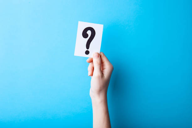 istock Woman holding card with question mark on color background. Paper note with question mark or sign against blue background. Ask or business concept 1248266199