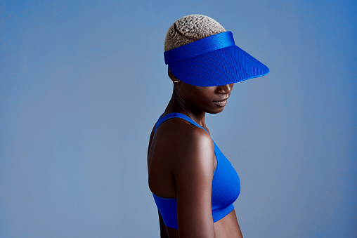 Studio shot of a sporty young woman wearing a visor while posing against a blue background