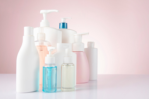 Hand sanitizers and antibacterial sprays on pink background