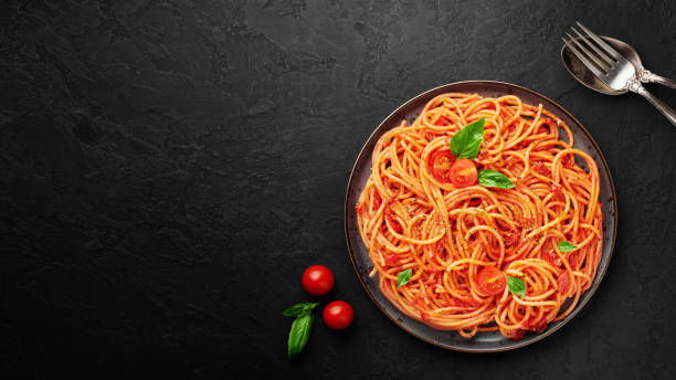 istock Tomato spaghetti on black plate on dark slate background. Tomato sauce pasta is classic italian cuisine dish. Popular italian food. Top view. Copy space 1248268030