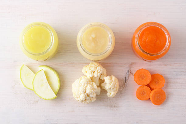 top view children's vegetable food on white background, natural homemade mashed zucchini cauliflower, carrots