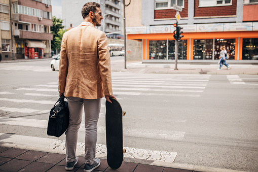 One men, young businessman with skateboard going to work, man walking in city.