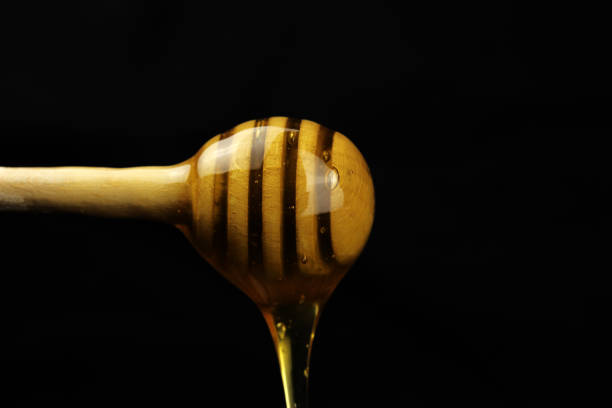 istock Honey dripping from a wooden stick on a black background 1248278534