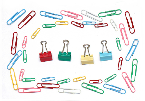 Colorful metal paper clips and pins stationery arranged in square on white background