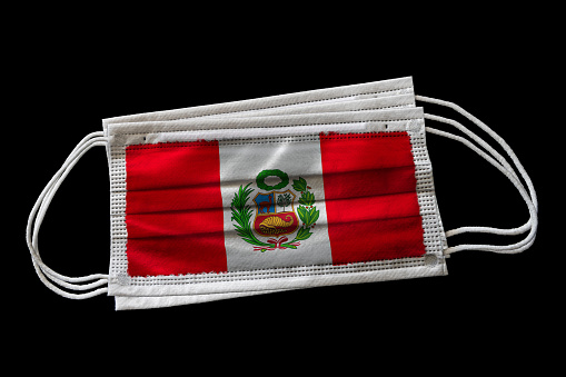 Surgical face masks with flag of Peru printed. Isolated on black background. Concept of face mask usage in the Peruvian effort to combat Covid-19 coronavirus pandemic.