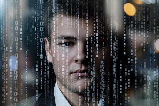 The face of a young businessman on a background of binary codes.