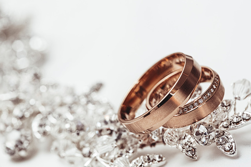 Two wedding rings on a piece of jewelry on white background.