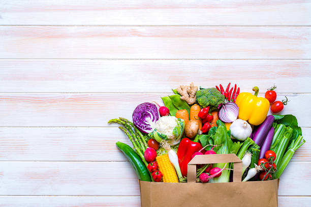 istock Shopping bag filled with fresh organic vegetables on white table. Copy space 1248285137