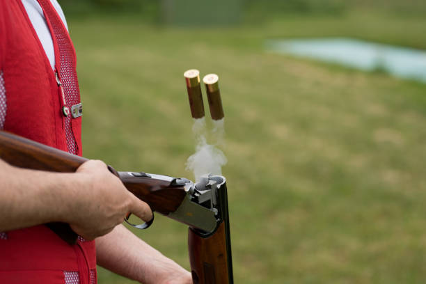 Rifle cartridges and smoke after firing. Man opens the shotgun bolt after  shot with smoke Rifle cartridges and smoke after firing. Man opens the shotgun bolt after  shot with smoke trap shooting stock pictures, royalty-free photos & images