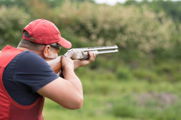 un hombre disparando alquito con una escopeta. disparos de skeet, disparos de trampa. - skeet shooting shooting clay target shooting fotografías e imágenes de stock