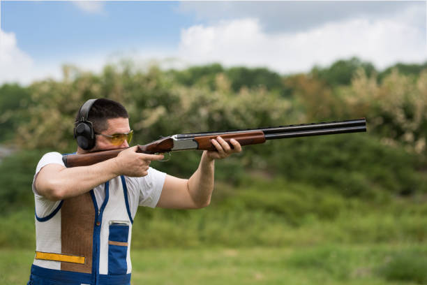 un hombre disparando alquito con una escopeta. disparos de skeet, disparos de trampa. - skeet shooting shooting clay target shooting fotografías e imágenes de stock