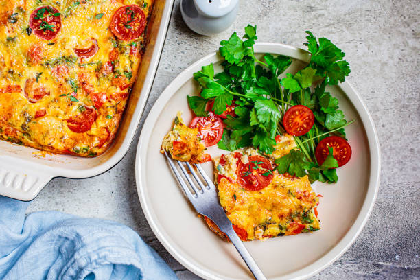 istock Classical baked frittata or omelet with tomatoes, peppers and cheese in white plate, light gray background. 1248291106