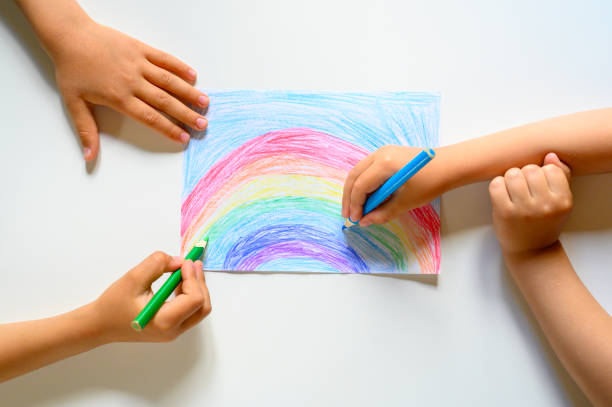 istock kid's hands together draw a rainbow colored pencils on white background 1248291175
