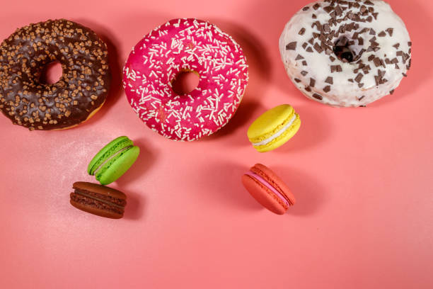 istock Tasty donuts and macaroons on pink background. Top view 1248293878