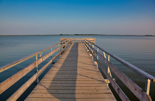 Old wooden pier with railing over calm water