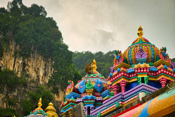 A monkey on top of a colorful Malaysian temple near Kuala Lumpur. Batu Caves.