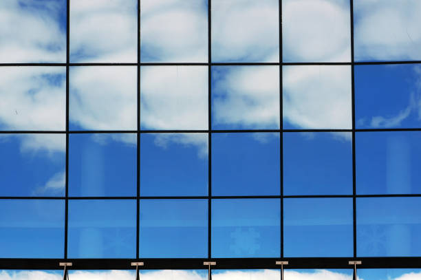 Reflections of blue sky and white clouds in big windows of modern building.